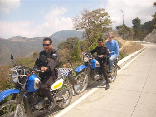 Eli (the one in the light blue shirt) on the back of motorcycle with Antigua police escorts/travel guides. 